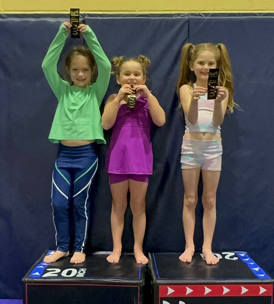 Students celebrating ribbon awards for milestone achievements in the CoachWayne® Gymnastics Skill Evaluation Program.